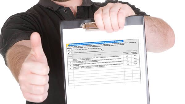 Engineer holding a completed EICR electrical installation condition report on a clipboard