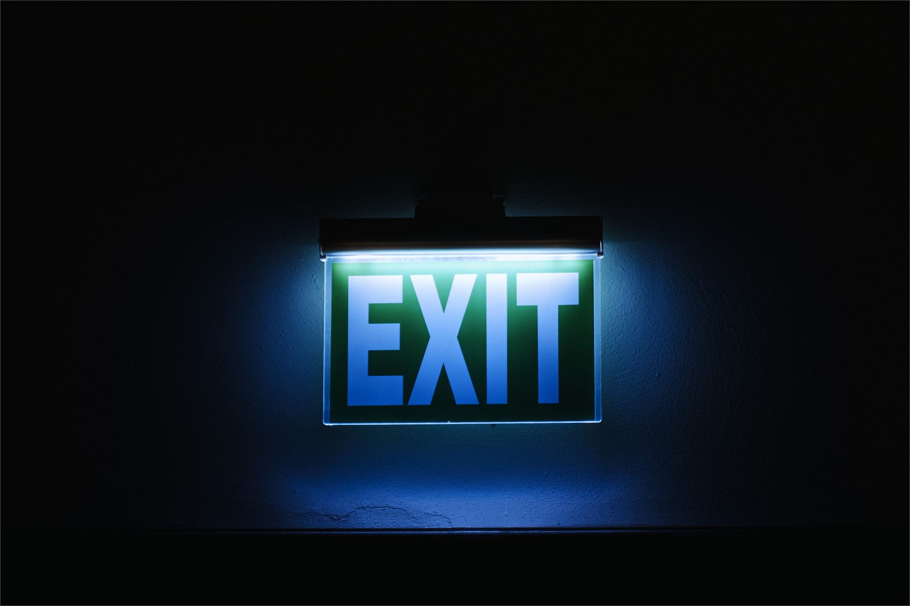 Illuminated green emergency exit sign in a darkened corridor