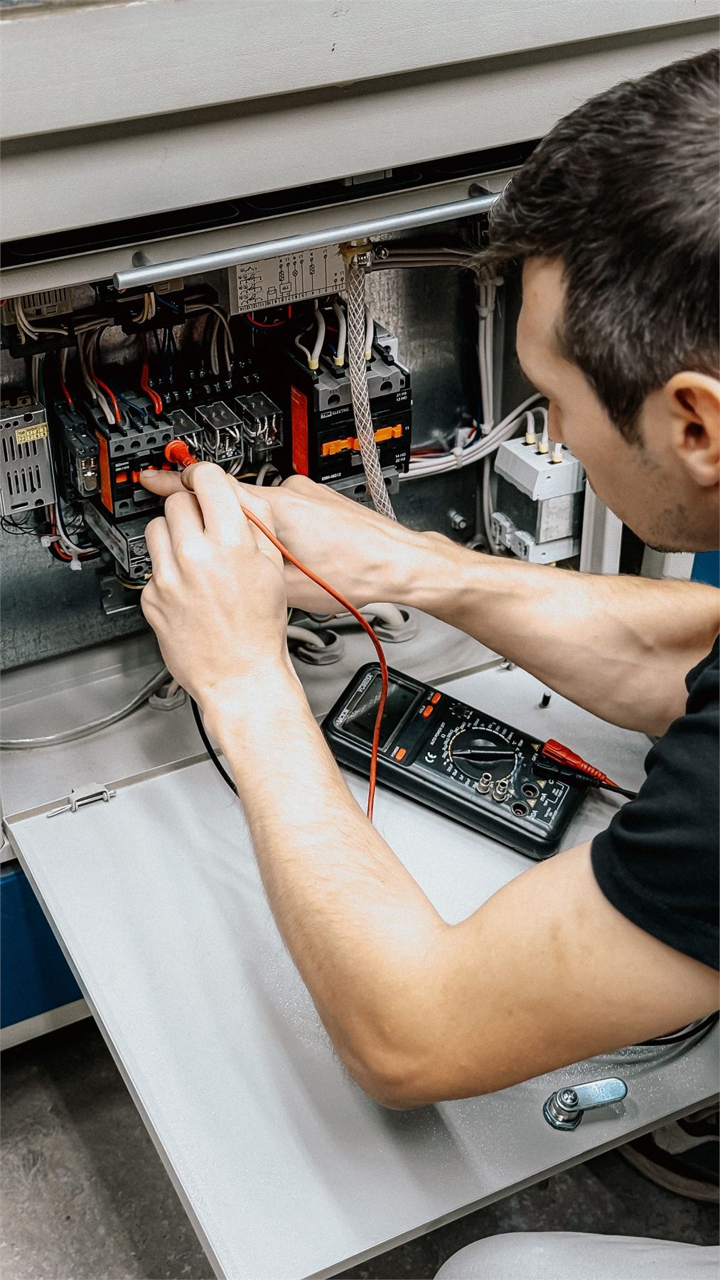 Qualified engineer testing a consumer unit with a multimeter during an electrical installation