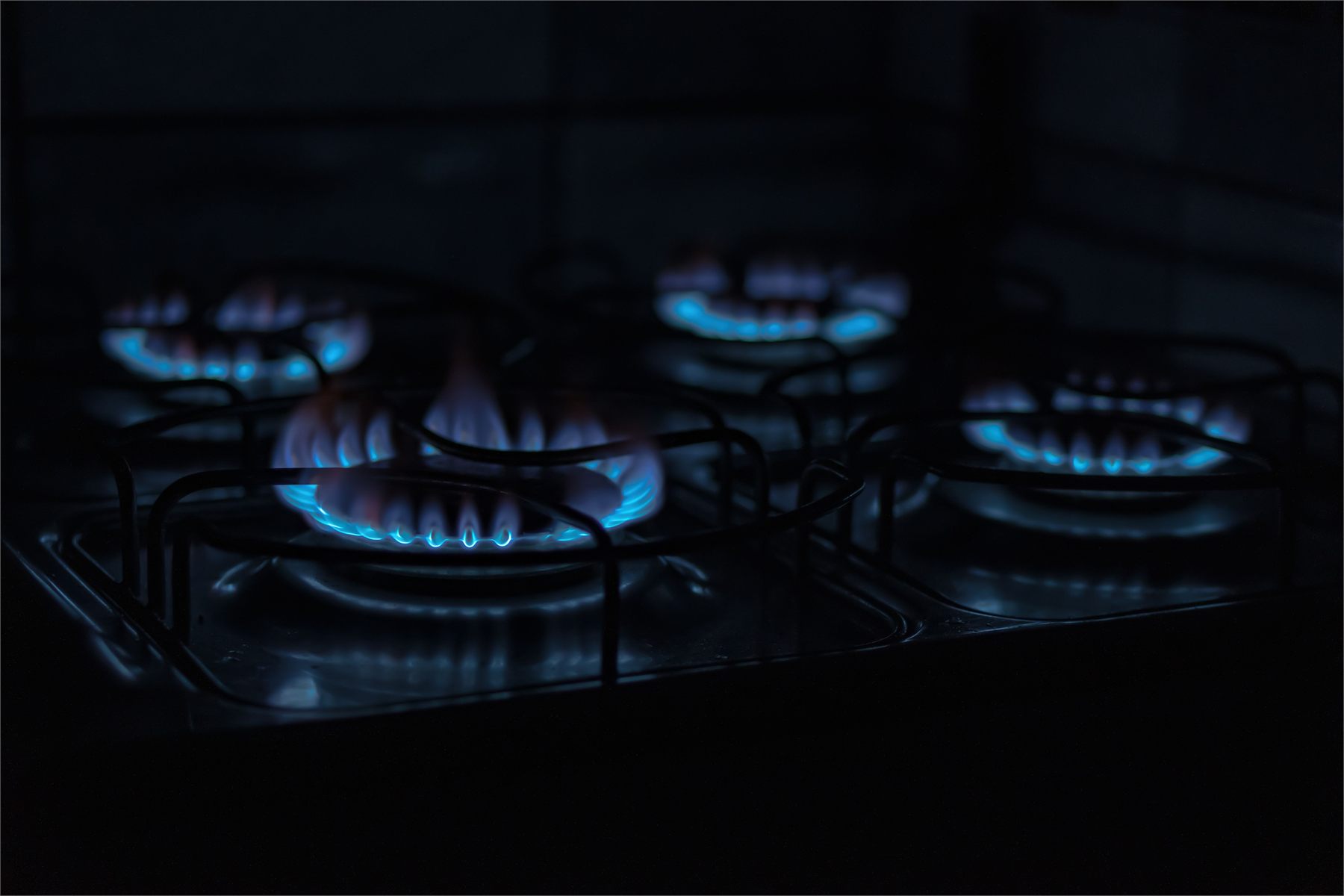 Blue gas hob flames burning on a domestic cooker during a gas safety check